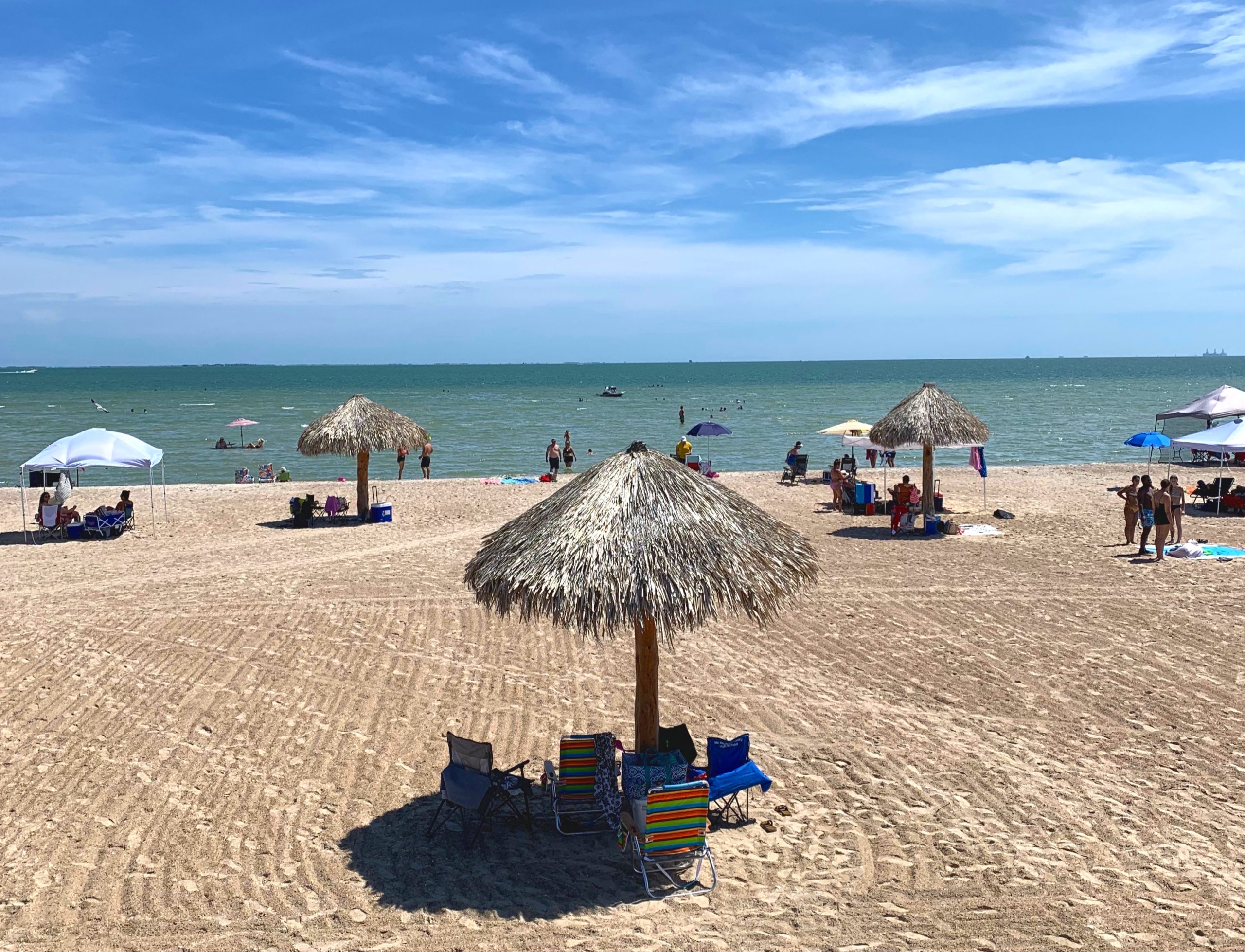 Rockport beach with multiple straw cabanas visible with the water in the background. visiting rockport beach is one of the most fun things to do in rockport tx
