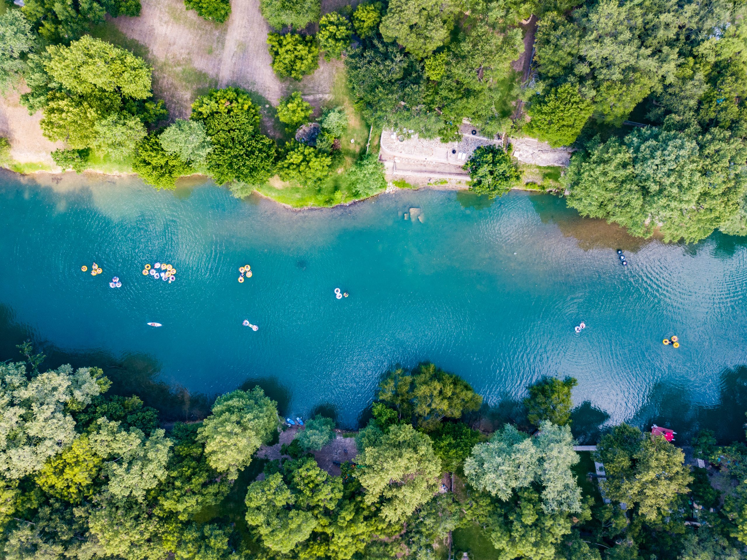 View of Guadalupe River from above with Texans floating on it. Guadalupe River State Park is one of the best day trips from San Antonio TX