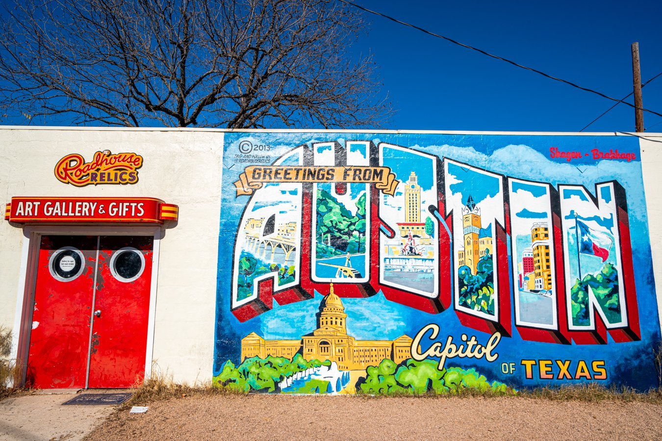greetings from austin mural on a sunny day with red roadside relics doors to the left