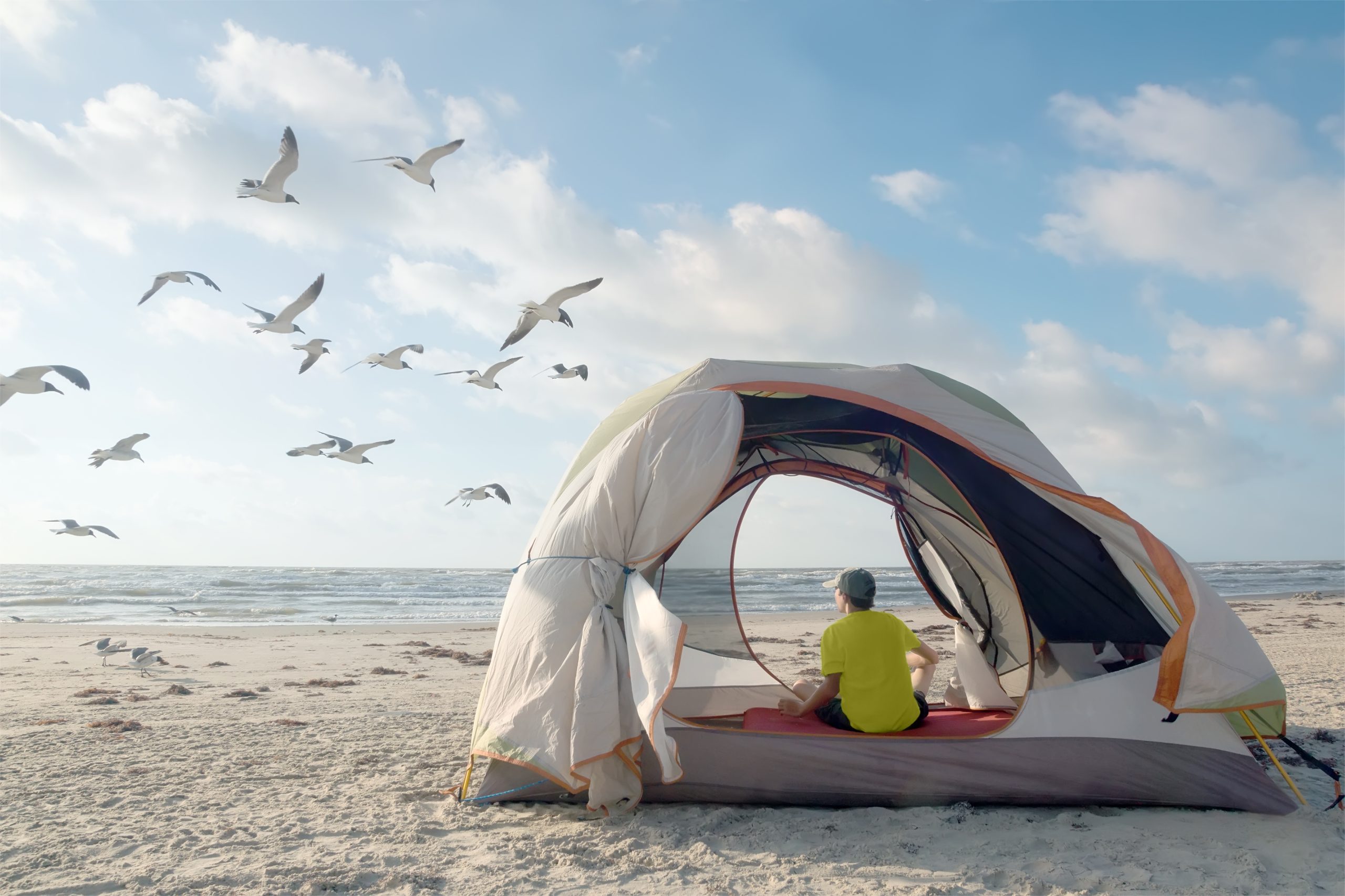 man in a tent on the beach on galveston island, one of the best parks for camping near houston texas