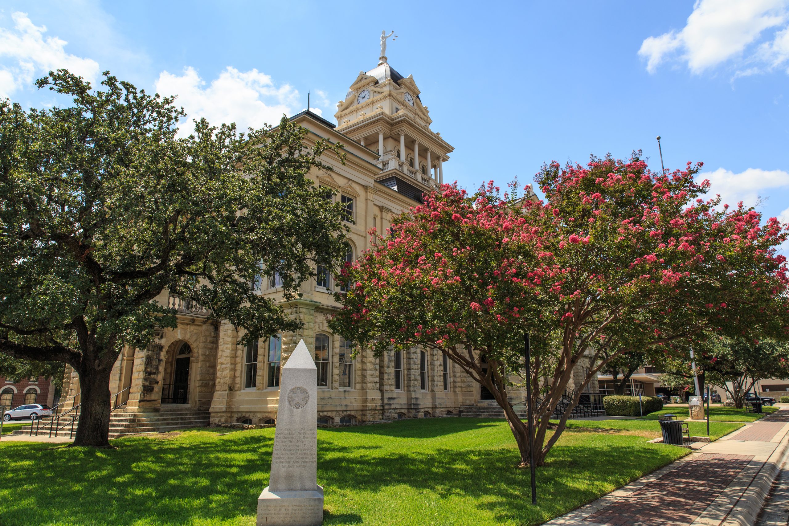 bell county courthouse with square, one of the best things to do in belton texas, with trees blooming pink flowers in the foreground